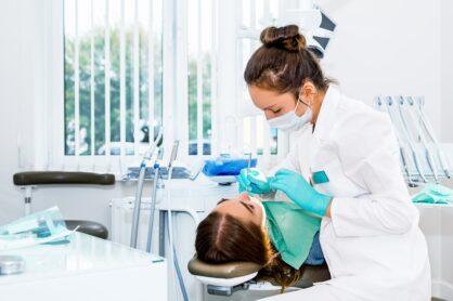 A female dentist carries out surgery on a female patient