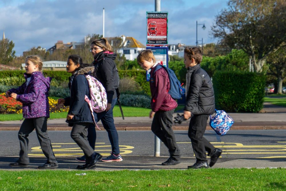 A group of British school children walking past a bus stop