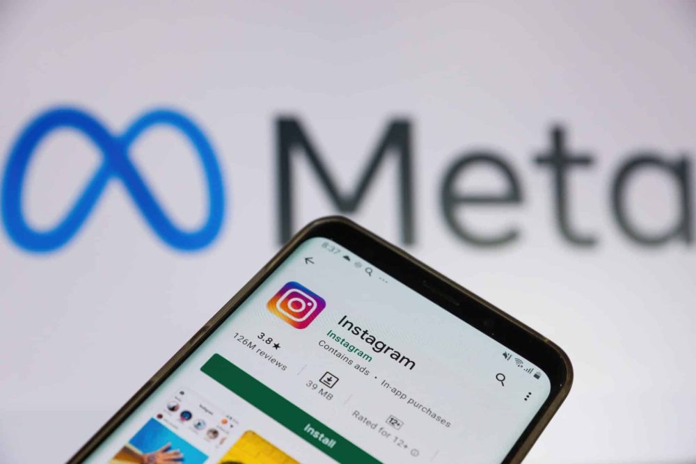 Smartphone screen with Instagram application on playstore and the logo of Meta on the background