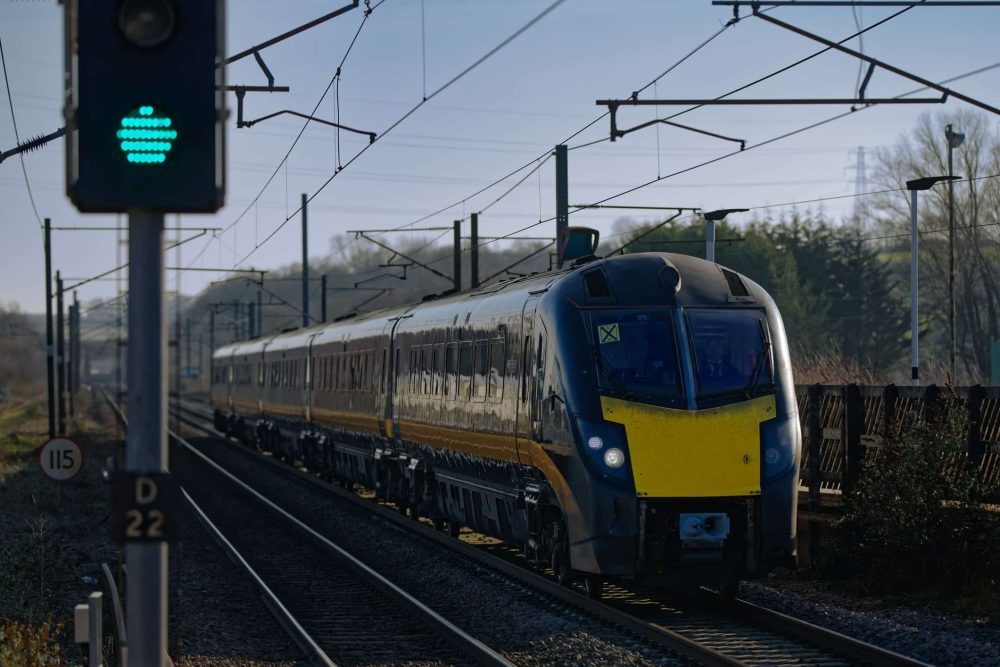 Passenger train in black and red Grand Central livery approaches Grantham Station