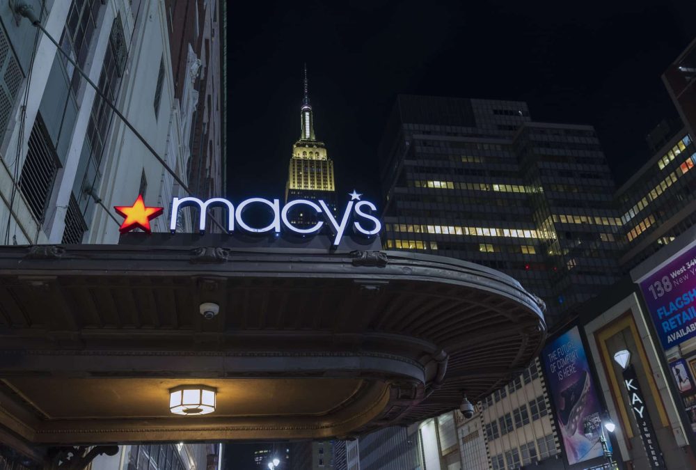 Macy`s sign on wall of store on background from on Empire State Building