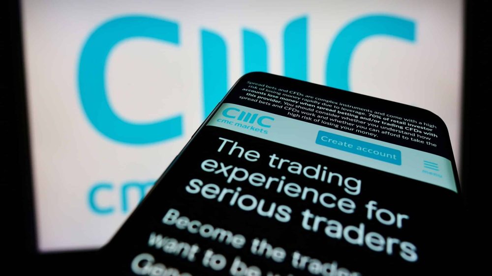 Phone with CMC Markets plc webpage with logo in the background