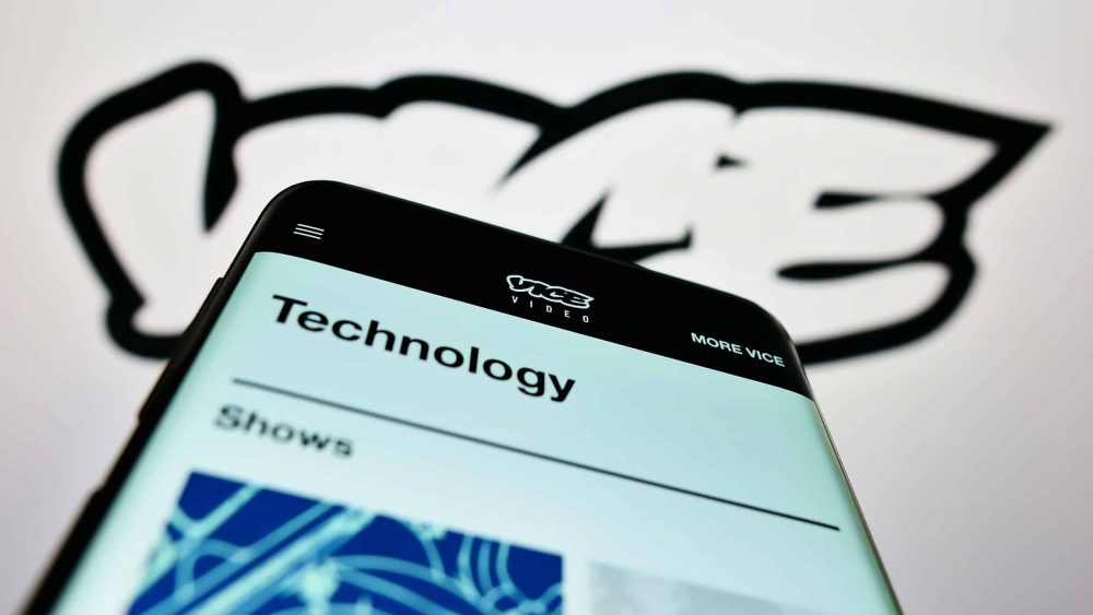 Vice Media webpage on phone screen against the company logo in the background