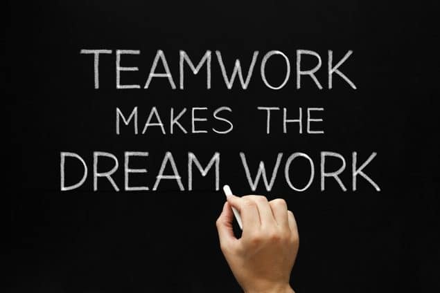 Somone writing Teamwork makes the dream work, with chalk