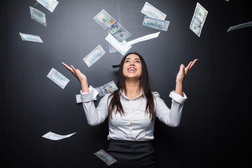 Happy business woman under a money rain made of dollars