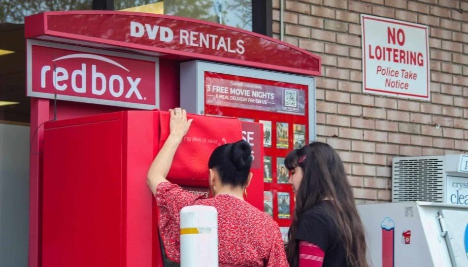 Two Women Using RedBox DVD Rental Kiosk