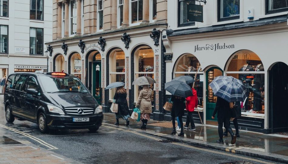 People with umbrella walking under the rain on Jermyn Street, London