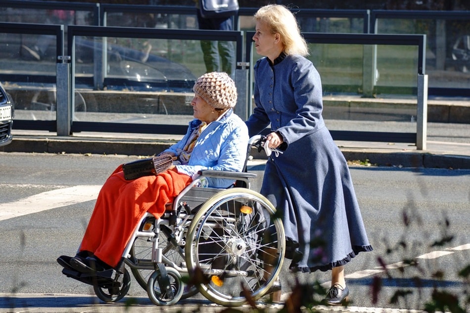 Woman pushing elderly woman in her wheelchair