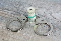 Cash tied up with a rubber band and between police cuffs