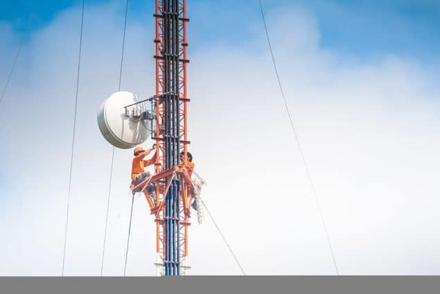 Two tower climbers work on a huge communications tower
