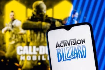 Activision Blizzard logo on smartphone screen and a frame from the Call of Duty on the background