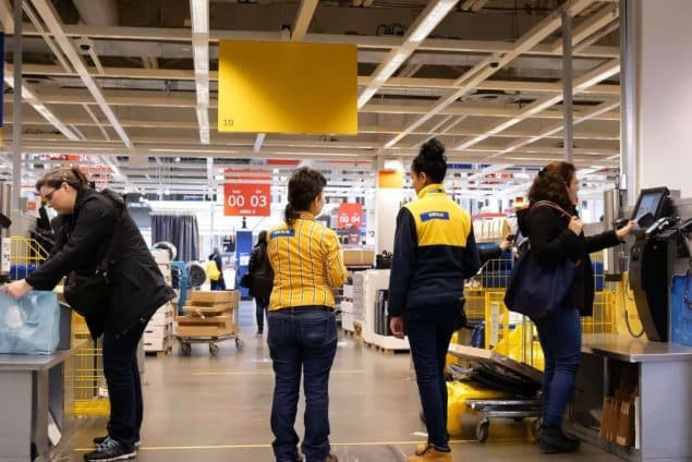 People paying product at self check out counter inside Ikea store