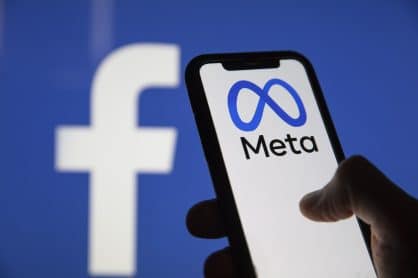 Smartphone with Meta logo placed against the background of Facebook logo