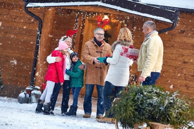 A family outside their house during the snow of Christmas season with gifts