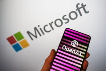 OpenAI logo on phone in a hand and blurred Microsoft logo on the background