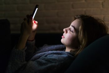 Woman using smart phone at night in bed