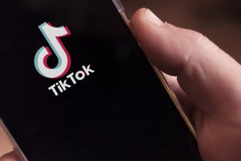 Hands holding phone with TikTok displayed on screen