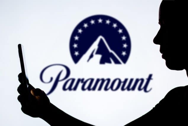 A woman's silhouette with a smartphone against the Paramount Global logo