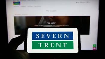 Person holding a phone displaying Severn Trent's logo on screen with its business webpage in the background.
