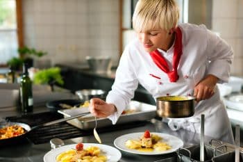 A blonde haired female chef serves up plates of food