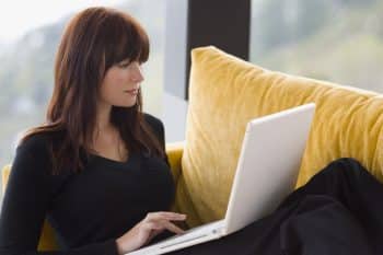 A woman works remotely from her sofa