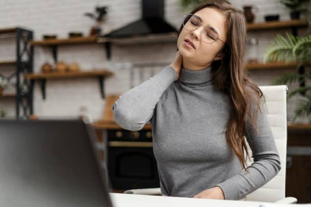 Young woman having a neckache while working from home