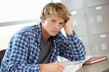 A teenage boy looks fed up with his homework